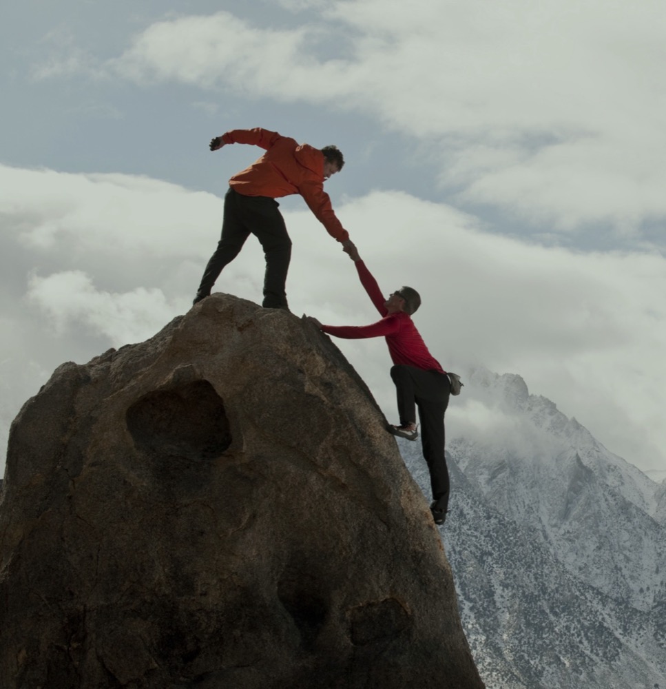 Climbers helping each other up a rock face